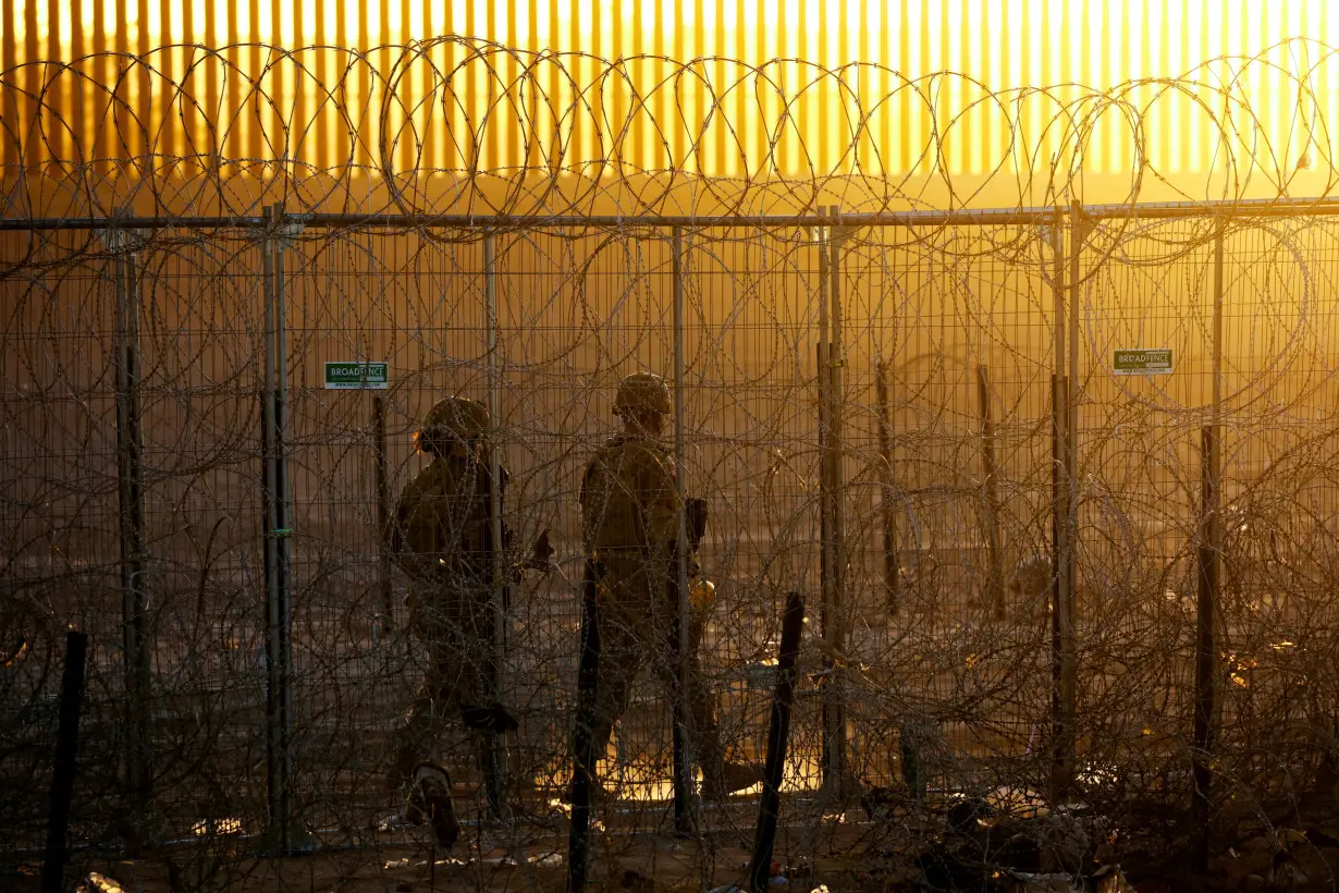 FILE PHOTO: Members of the Texas National Guard stand guard near a razor wire fence to inhibit the crossing of migrants into the United States, seen from Ciudad Juarez