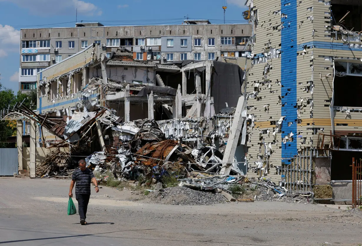 FILE PHOTO: A man walks past a destroyed building in Mariupol