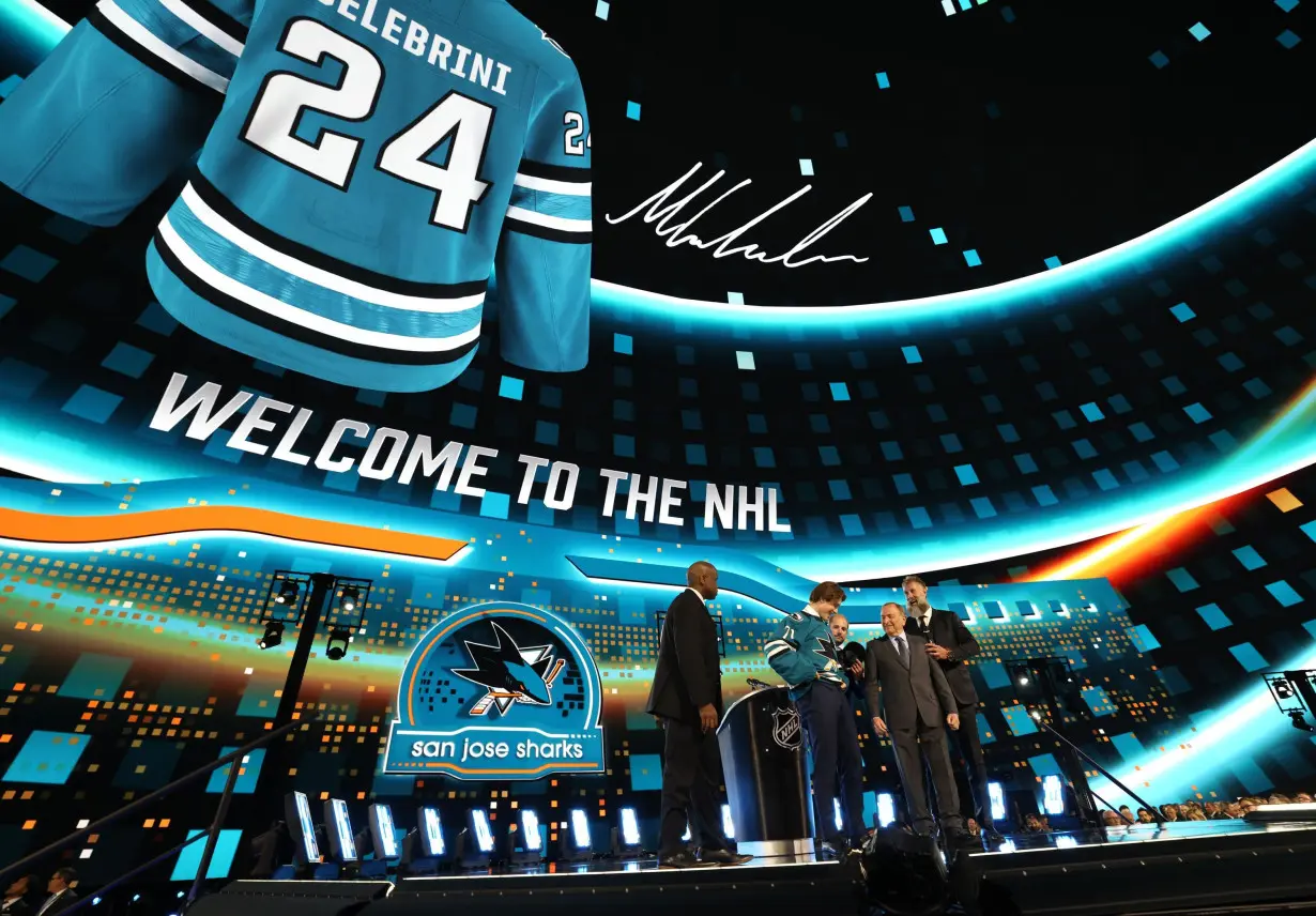 Macklin Celebrini puts on a jersey after being selected first overall by the San Jose Sharks during the first round of the 2024 NHL Draft at Sphere on June 28, 2024, in Las Vegas, Nevada.