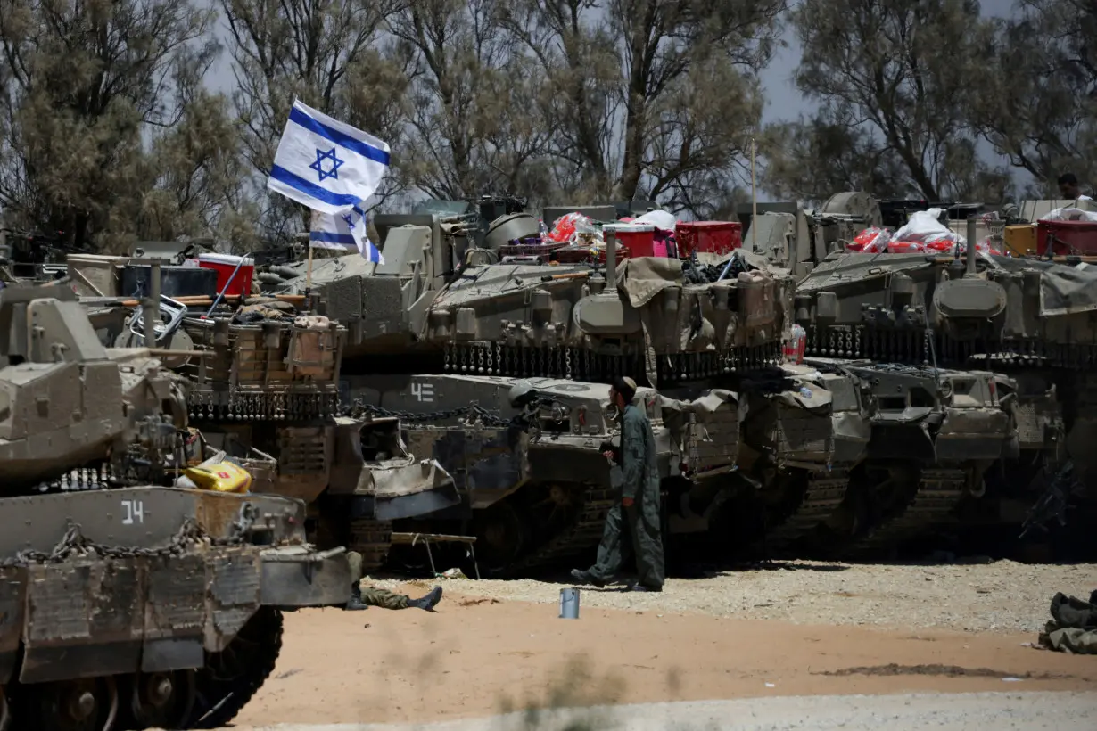 FILE PHOTO: An Israeli soldier walks near military vehicles, amid the ongoing conflict between Israel and the Palestinian Islamist group Hamas, near Israel's border with Gaza in southern Israel