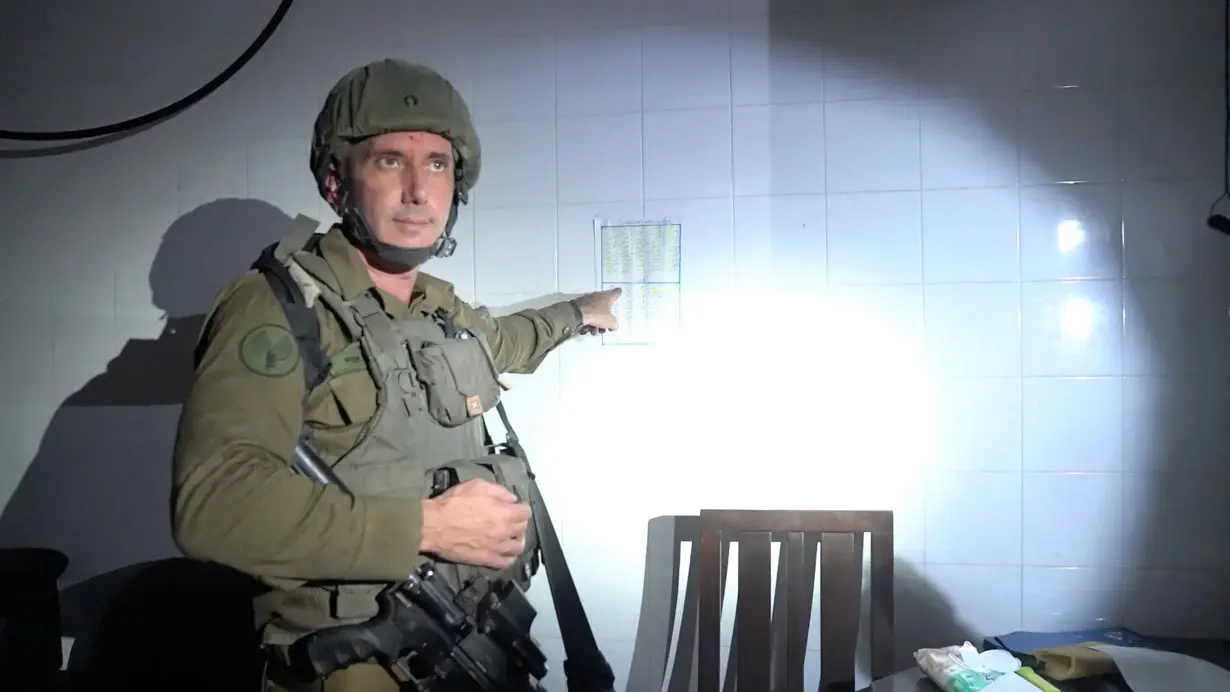 Israeli military spokesperson Rear Admiral Daniel Hagari points at what he says is a guard roster in a room the military suspects was used by Hamas to hold hostages in the basement of Rantissi Hospital