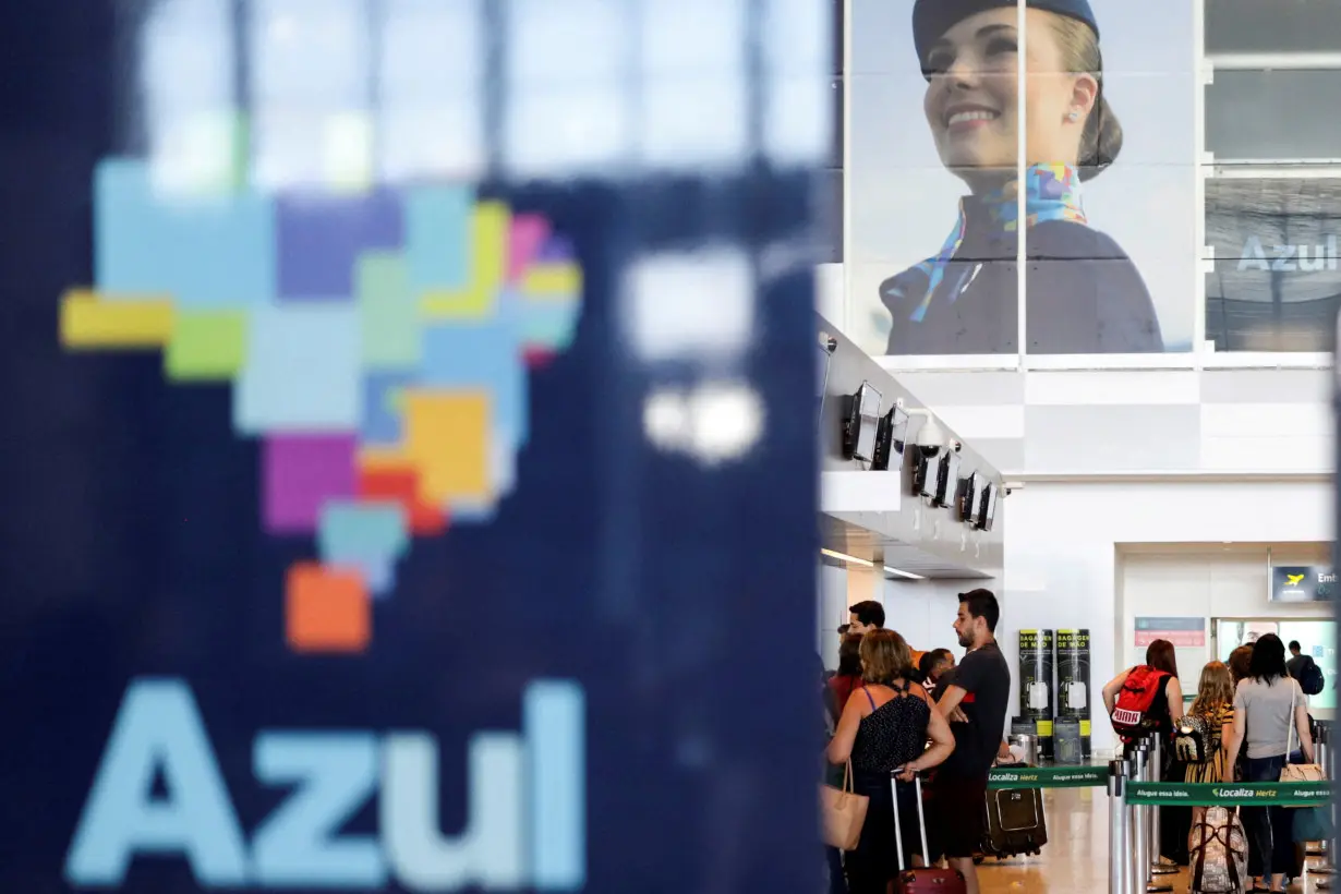 FILE PHOTO: Passengers stand near a Brazilian airline Azul signage, after the airline stated that it will cut all of its international flights out from its main hub due to the coronavirus outbreak, at Viracopos International Airport, in Campinas