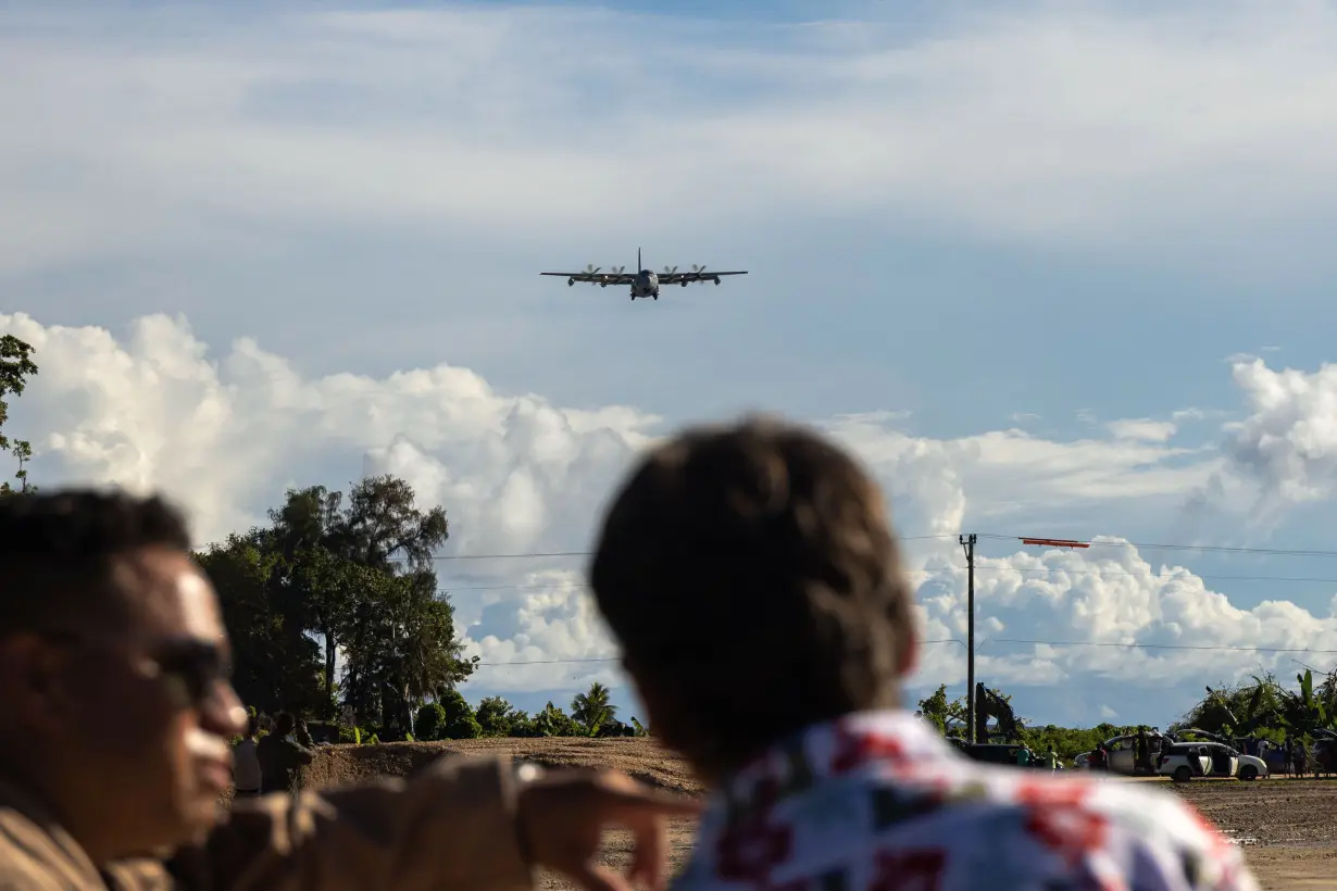 US Marines, sailors, and local residents observe a Marine Corps KC-130J Super Hercules aircraft with 1st Marine Air Wing land on a newly designated airstrip on the island of Peleliu on June 22.