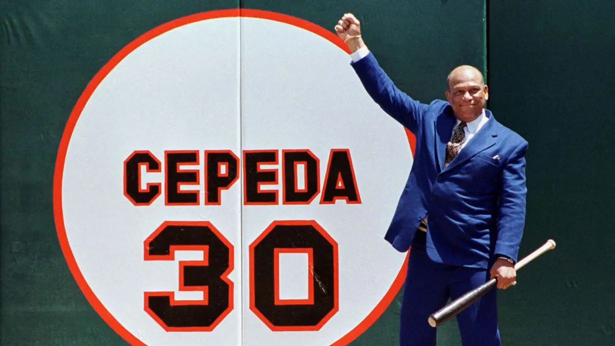 Former San Francisco Giants star Orlando Cepeda pumps his fist in the air as he stands in front of his old number 30, painted on the right field wall during a ceremony in which his number was retired at 3Com Park in San Fransisco, California, on July 11, 1999.