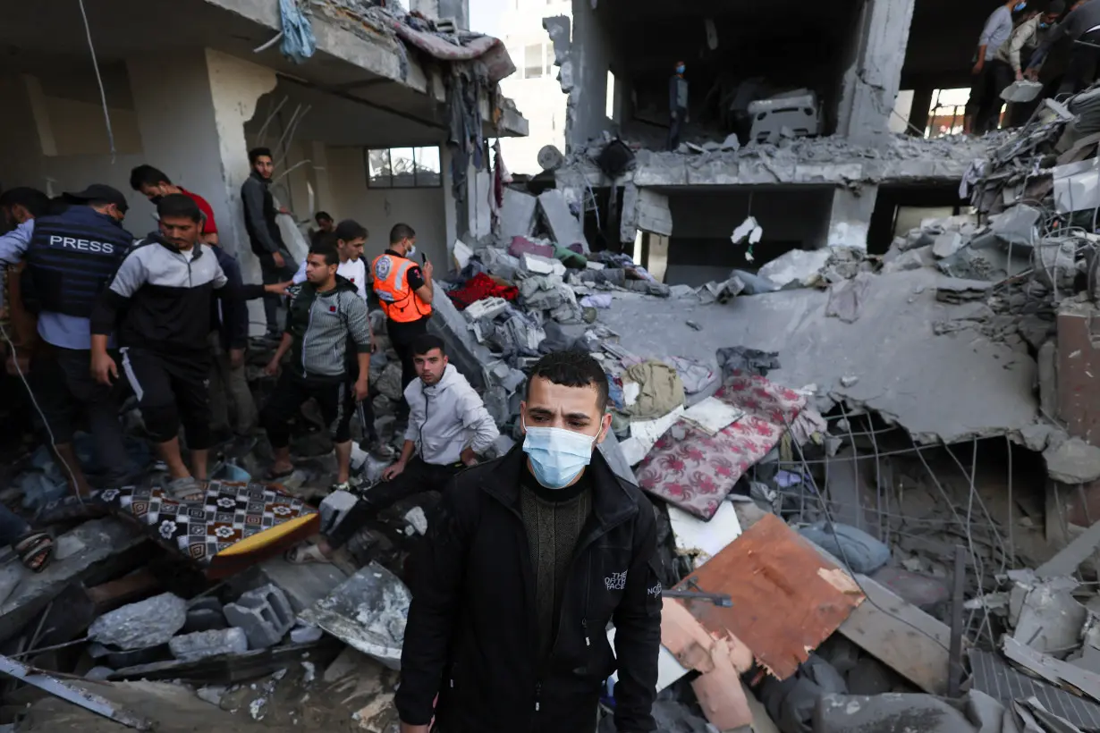 A Palestinian man wears a protective face mask as others search for casualties at the site of an Israeli strike on a house in Rafah, amid the ongoing conflict between Israel and the Palestinian Islamist group Hamas, in the southern Gaza Strip