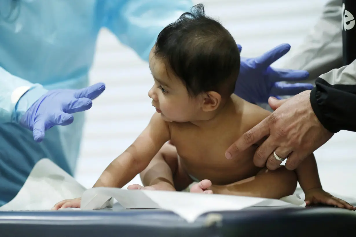 FILE PHOTO: Dr Greg Gulbransen performs a routine checkup with a baby while maintaining visits with both his regular patients and those confirmed to have the coronavirus disease (COVID19) at his pediatric practice in Oyster Bay, New York