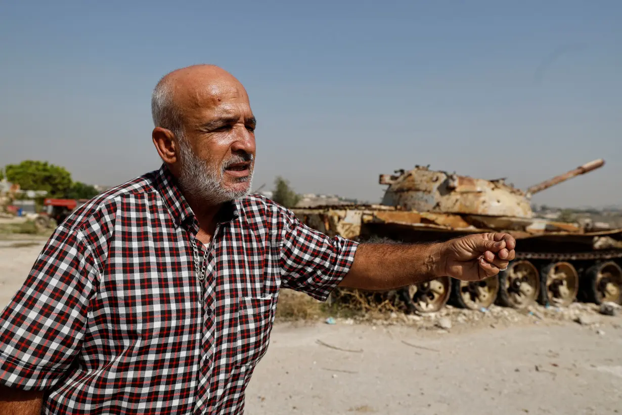 Jamil Salameh, 56, who witnessed the Israeli shelling that killed more than 100 people in 1996 and dozens more in an Israeli airstrike in 2006, talks to a journalist beside what he said the remains of a destroyed Israeli tank in Qana