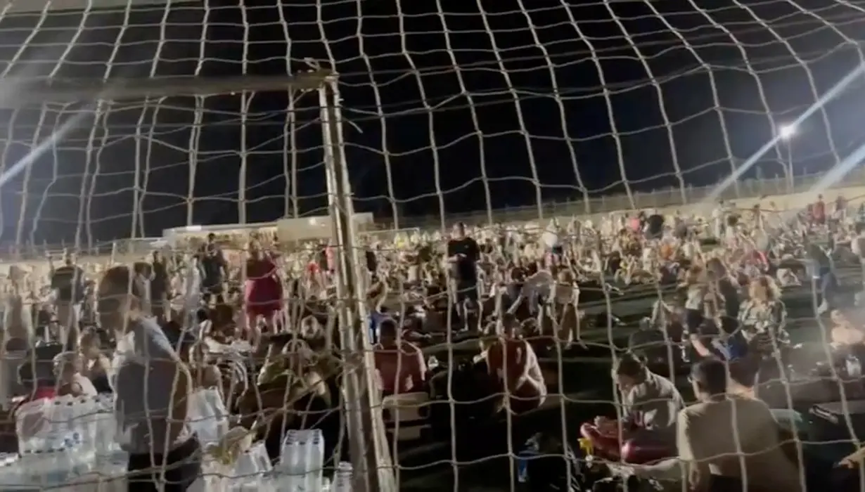 People gather at a football field following fire around the island of Kos
