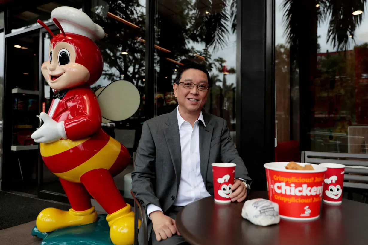 FILE PHOTO: Ernesto Tanmantiong, President and CEO of Philippine national champion Jollibee Foods Corp., poses with Jollibee products outside a Jollibee branch in Pasig City