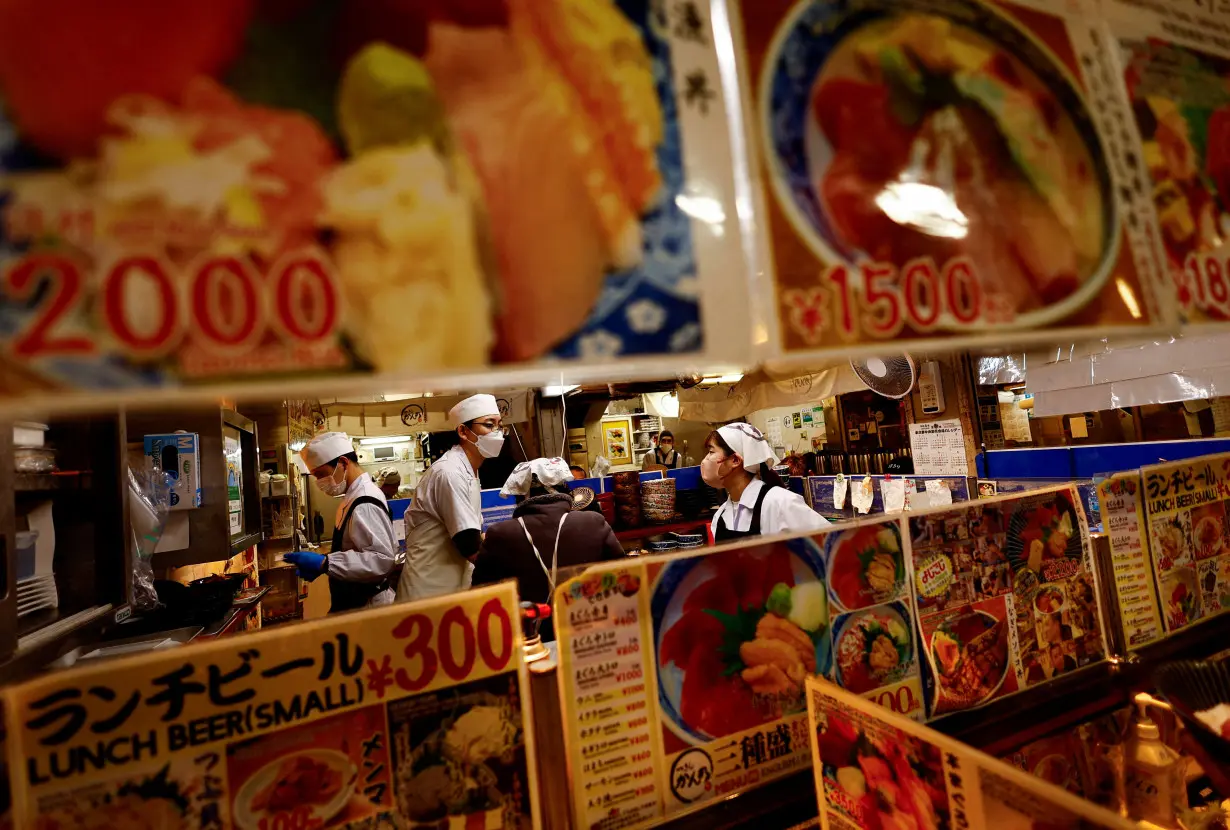 FILE PHOTO: Employees of a seafood restaurant work in their kitchen space at Tsukiji Outer Market in Tokyo