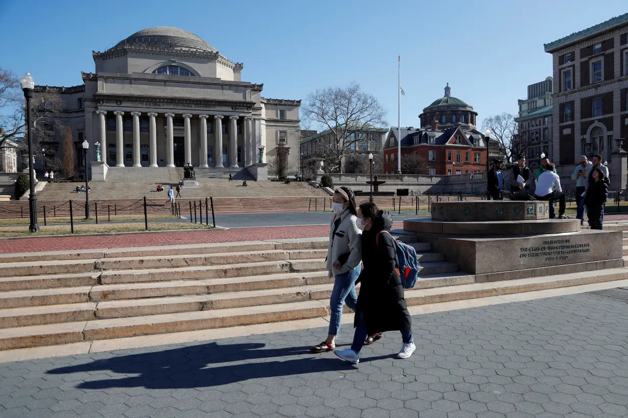 FILE PHOTO: People with face masks walk at Columbia University in New York City, where classes on Monday and Tuesday were suspended because someone on the campus was under quarantine from exposure to the coronavirus