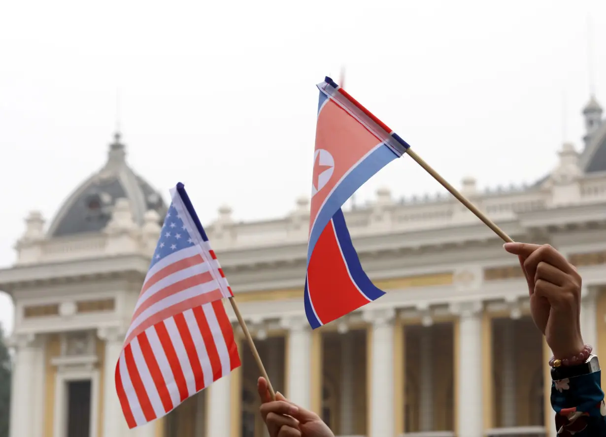 Residents hold US and North Korean flags while they wait for motorcade of North Korea's leader Kim Jong Un en route to the Metropole Hotel for the second US- North Korea summit in Hanoi