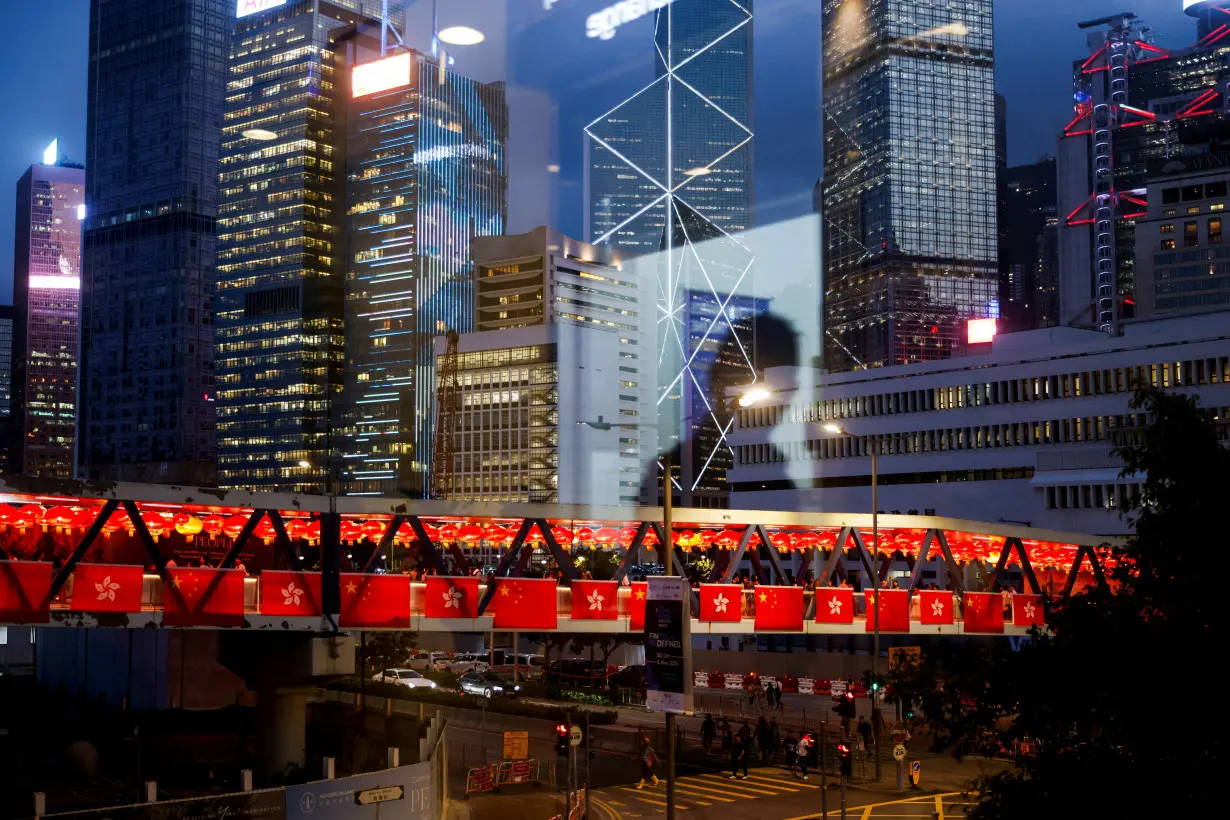 Reflection of a man is seen on the glass, while a pedestrian footbridge in the background is adorned with China's and Hong Kong's flags as decorations for the celebration of National Day, in Hong Kong