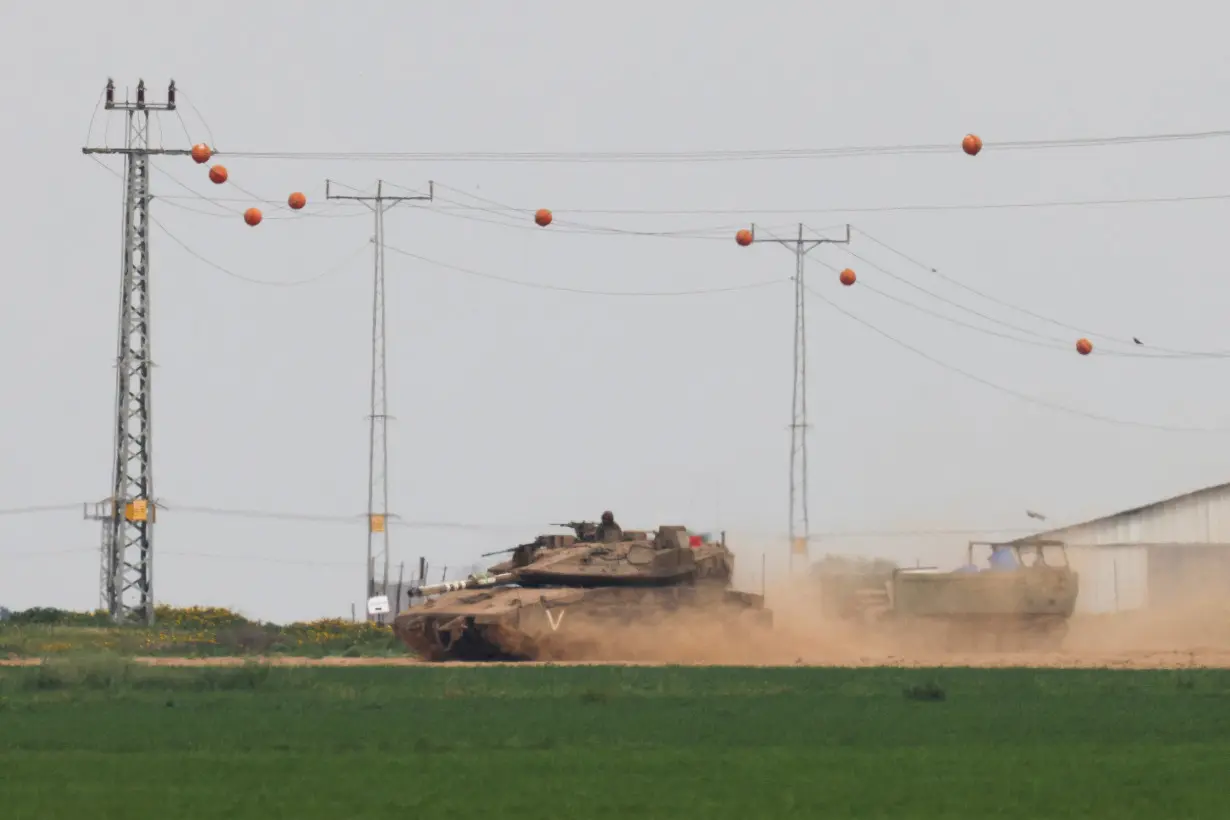 An Israeli tank pulls an armoured personnel carrier (APC) near the Israel-Gaza border, amid the ongoing conflict between Israel and the Palestinian Islamist group Hamas, as seen from Israel