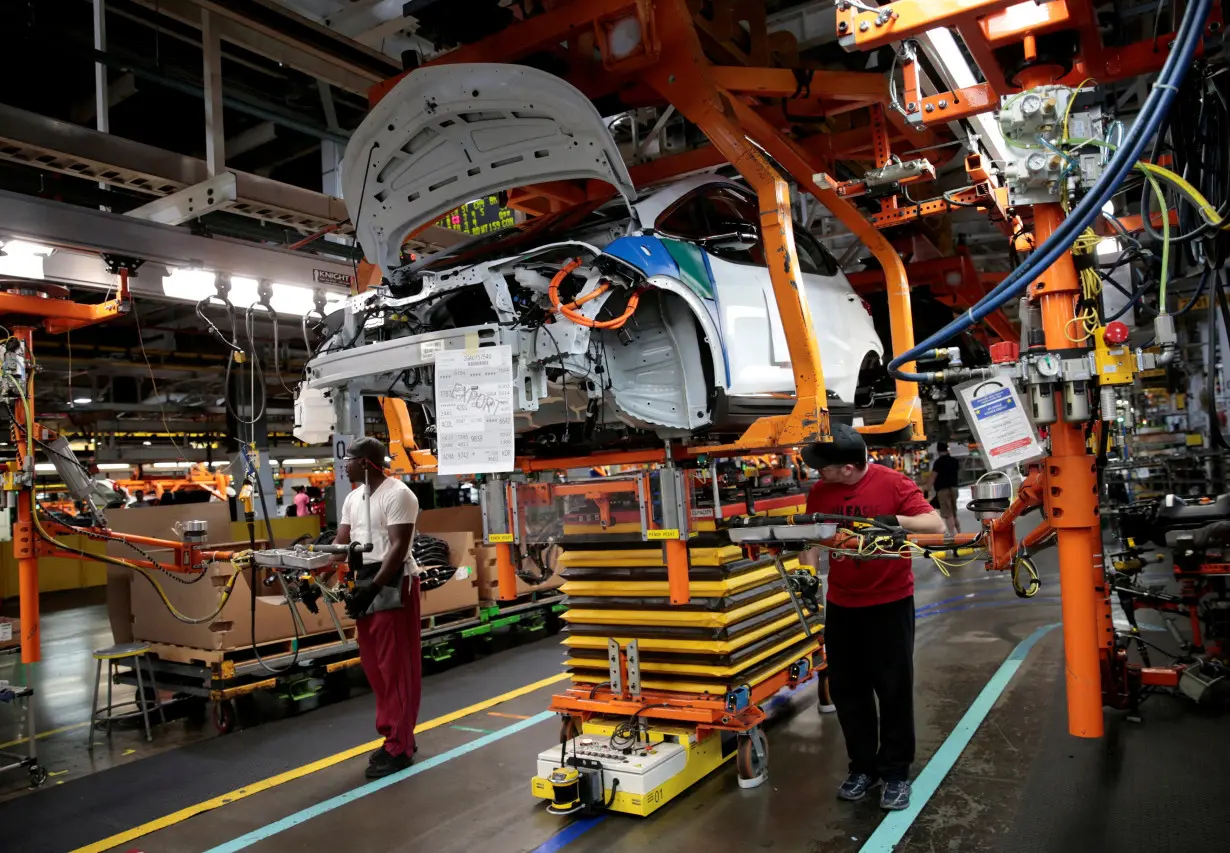 FILE PHOTO: General Motors assembly workers connect a battery pack underneath a partially assembled 2018 Chevrolet Bolt EV vehicle on the assembly line at Orion Assembly in Lake Orion,
