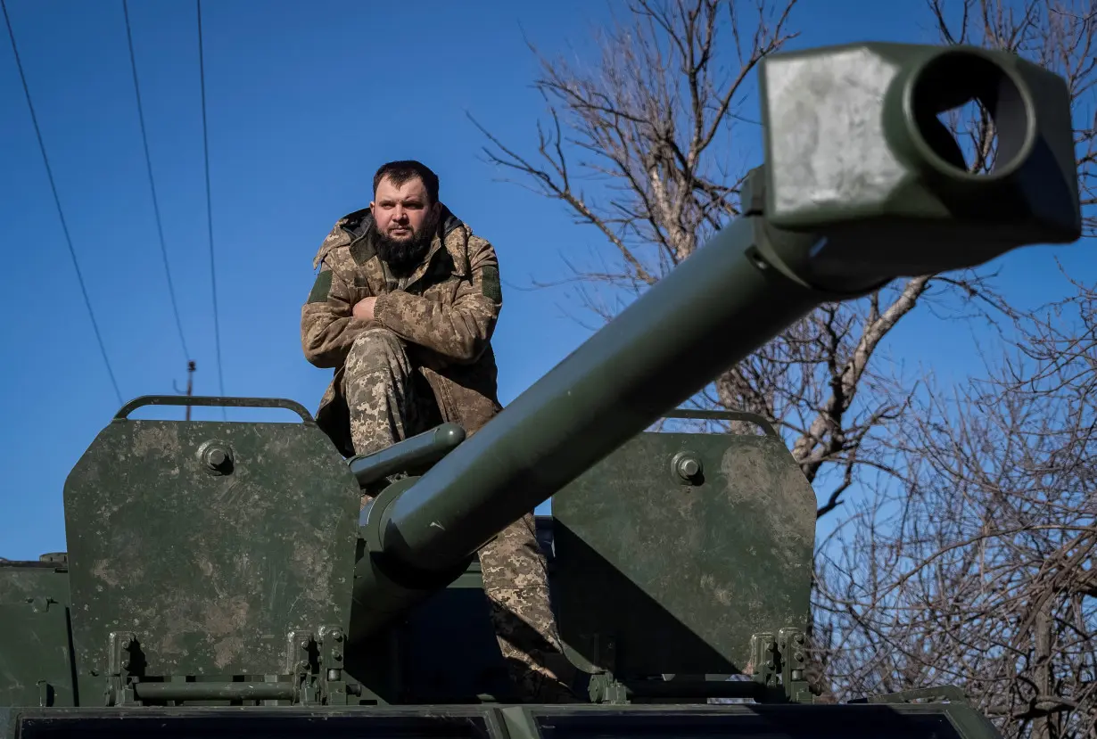 A Ukrainian serviceman sits a top of a self-propelled howitzer in Bakhmut