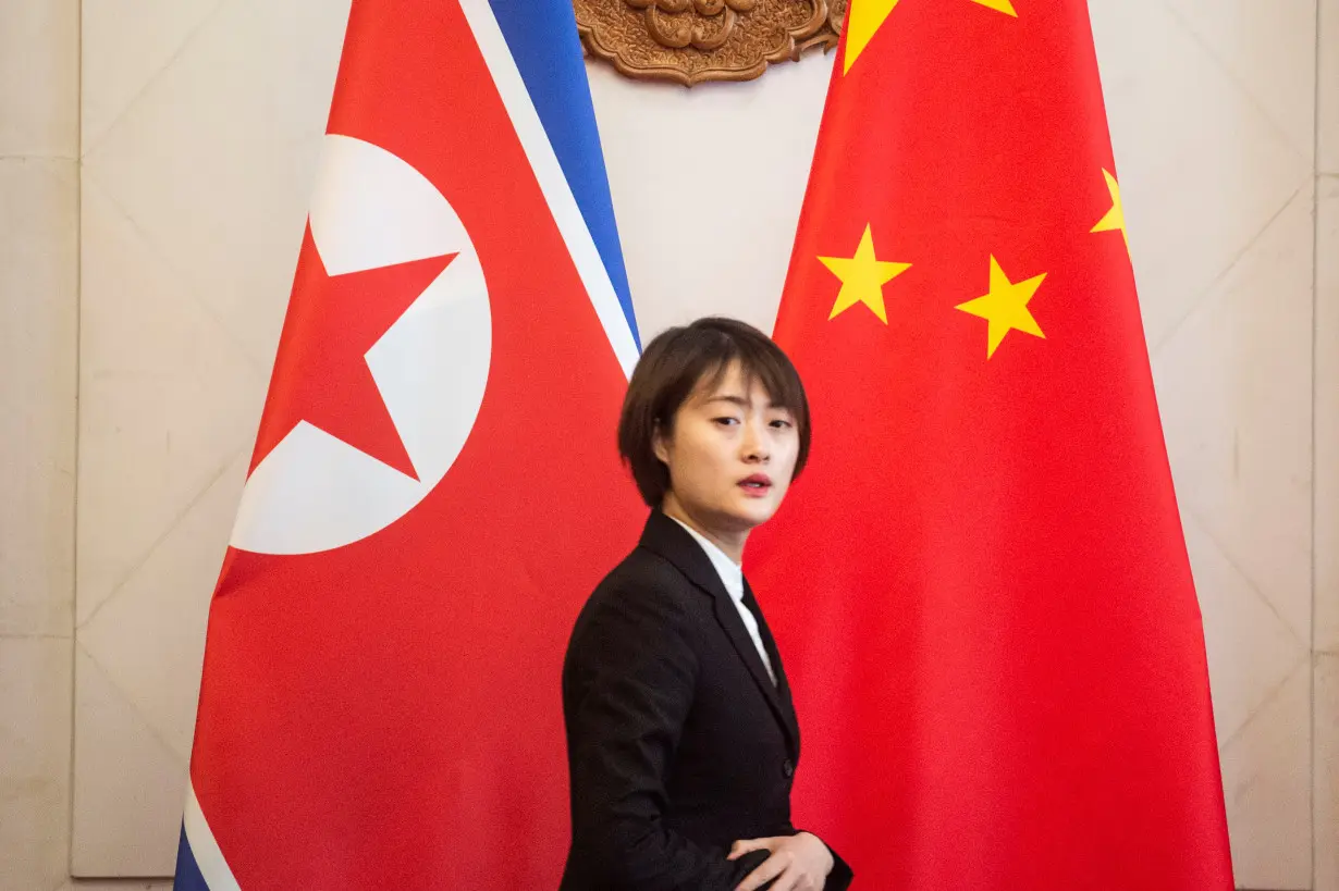 A Chinese hostess walks past North Korean and Chinese flags before the meeting between North Korean Foreign Minister Ri Yong Ho and China's Foreign Minister Wang Yi at the Diaoyutai State Guesthouse in Beijing