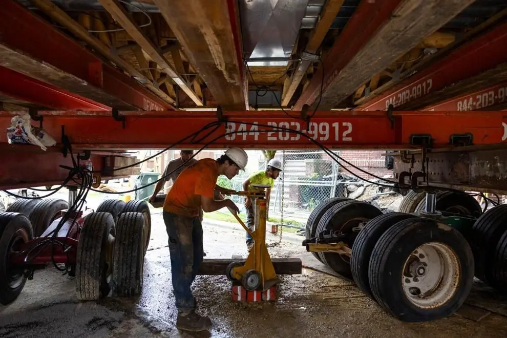 Crew members adjust one of the dollies holding up the 400-ton apartment building being moved Thursday. The building's owner said it's the heaviest building ever moved in Madison.