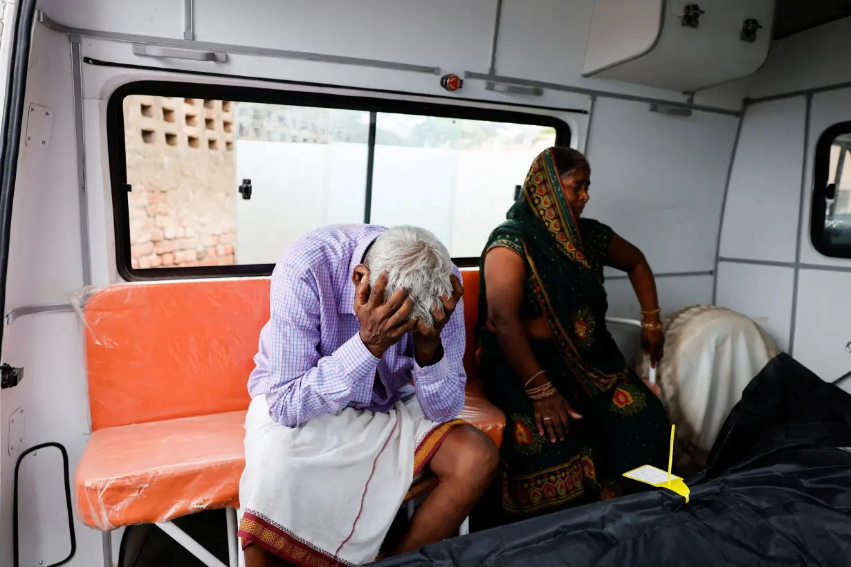 Relatives of a crush victim mourn next to her body, outside a hospital in Hathras district.