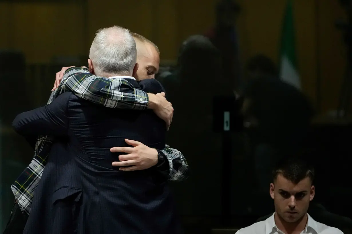 Ethan Elder, back to camera, hugs his son Finnegan Lee Elder before the reading of the judgment in Rome, Italy, on July 3, 2024. At right sits Gabriel Natale Hjorth.