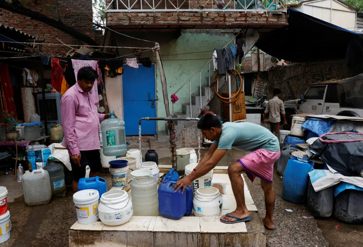 Residents fill their containers from a tap that dispenses water twice a day at a slum in New Delhi