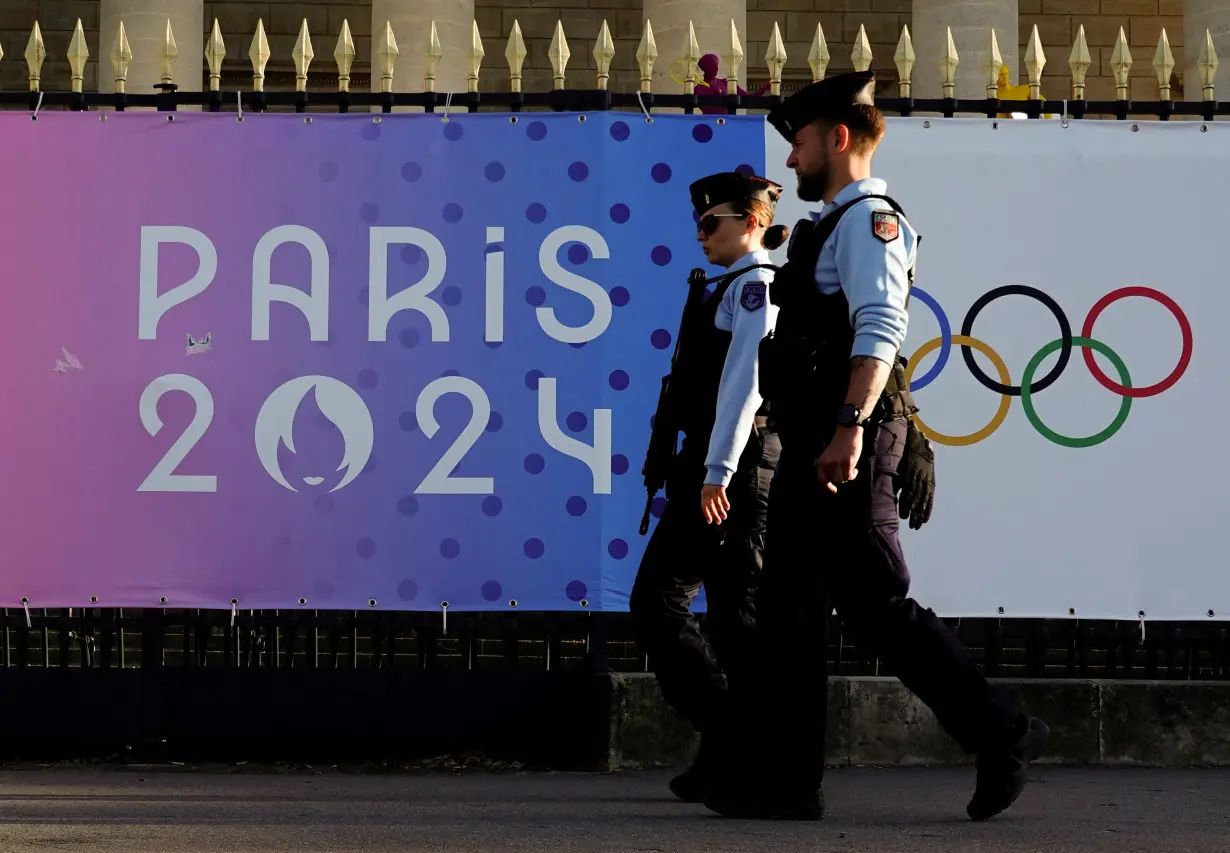FILE PHOTO: French gendarmes patrol a street near a poster advertising the Paris 2024 Summer Games in Paris