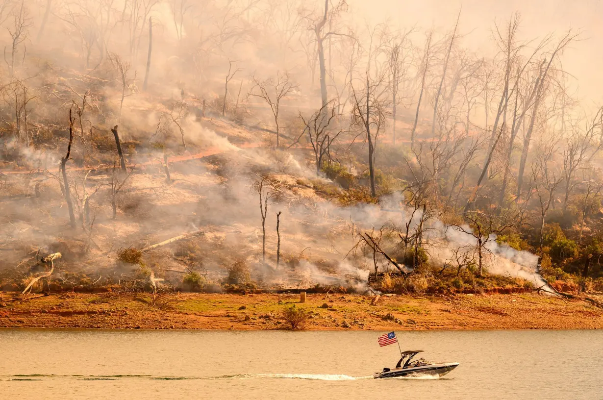 A boat moves along Lake Oroville as the Thompson Fire continues to burn in Oroville, California on July 3.