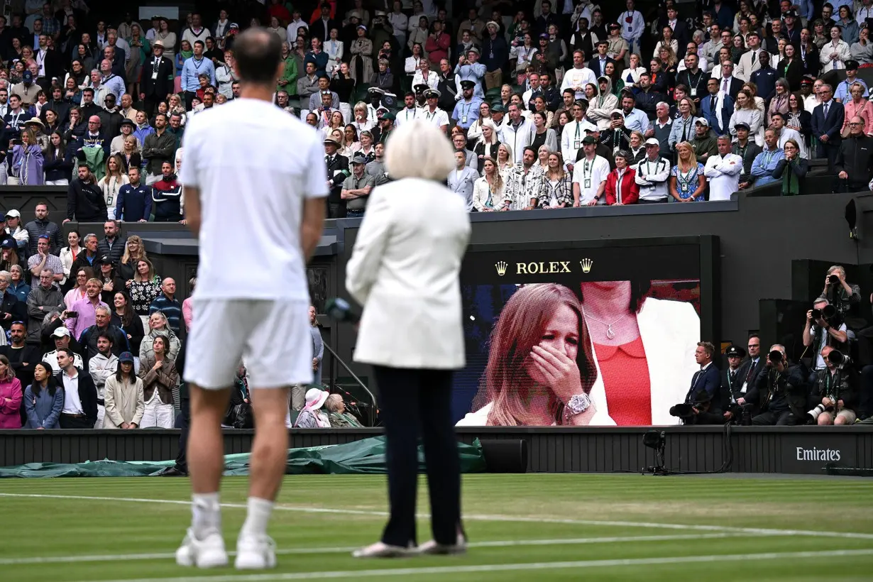 Murray watches on as a video montage of his career highlights plays on the big screens at Wimbledon.