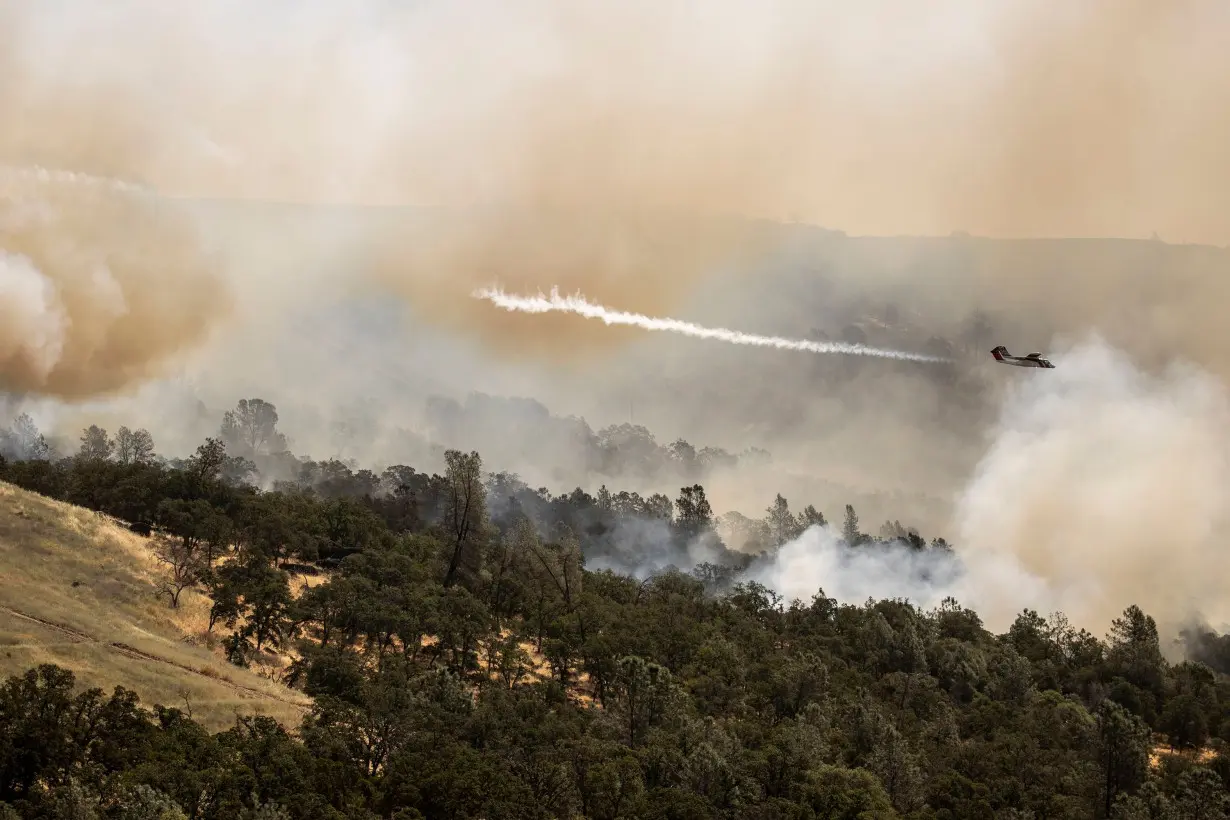 A Cal Fire air tactical aircraft releases a puff of smoke while guiding a fire retardant drop during the Thompson Fire, in Oroville, California, on Wednesday.