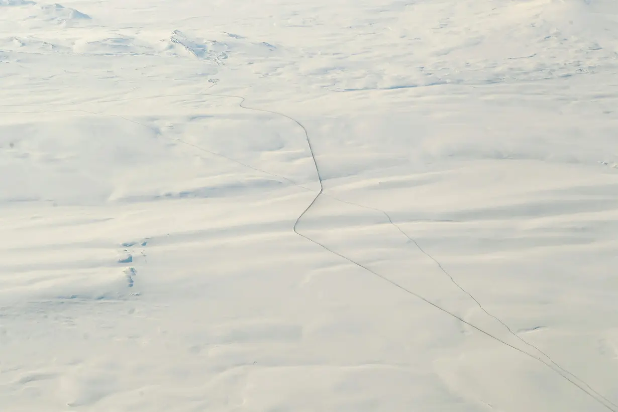 A road and the Trans Alaska Pipeline run over the tundra in northern Alaska