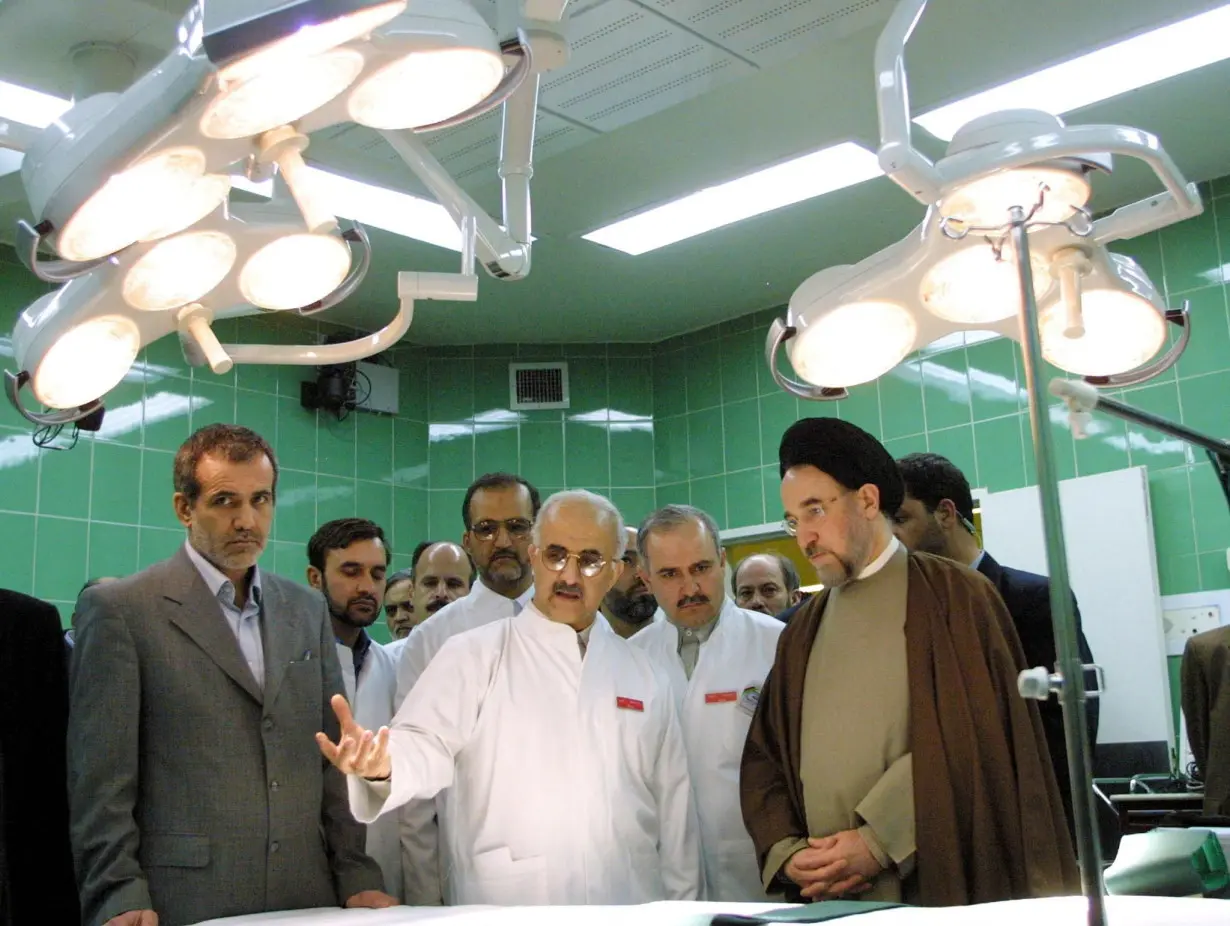 In this 2002 file photo, then-Health Minister Masoud Pezeshkian, left, and then-Iranian President Mohammad Khatami, right, listen to Abbas-Ali Karimi, center, head of Tehran's Cardiology Center, as they visit an operating room during the center's inauguration.