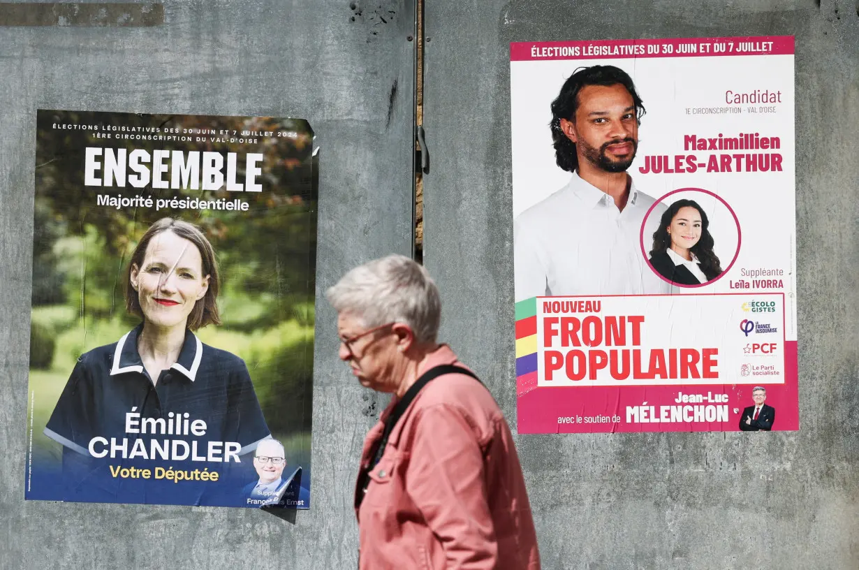 A person walks past election campaign posters prior to the second round of the early French parliamentary elections, in Magny-en-Vexin