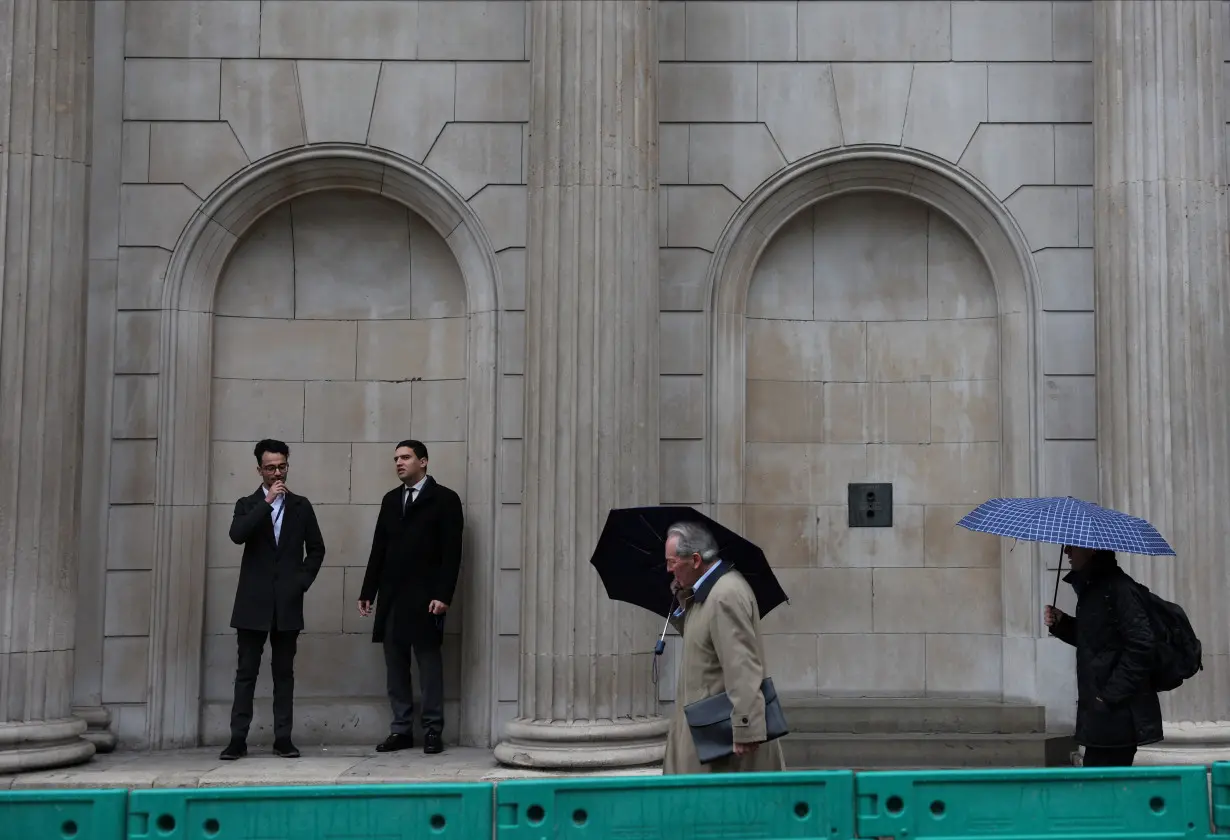 Commuters walk pass the Bank of England in the City of London financial district in London