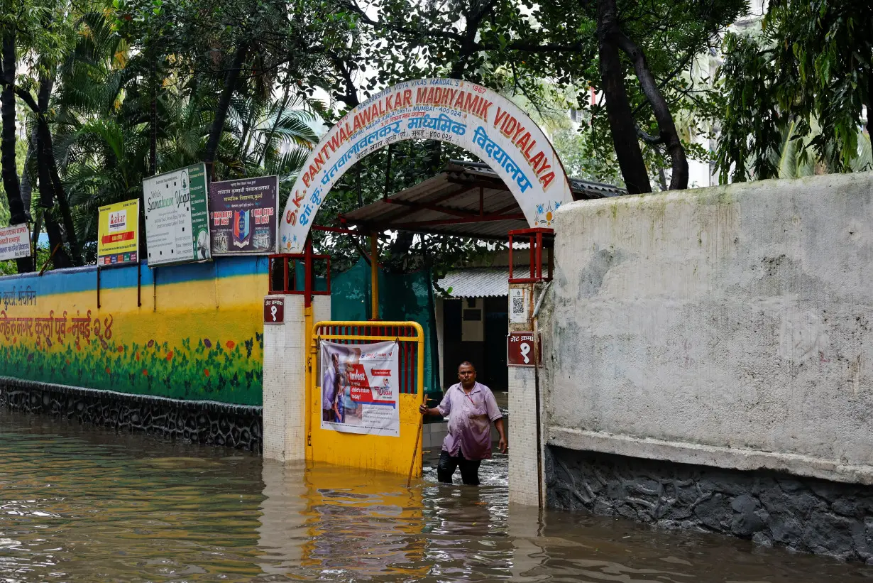 A man stands at the entrance of a school on a waterlogged street after heavy rains in Mumbai