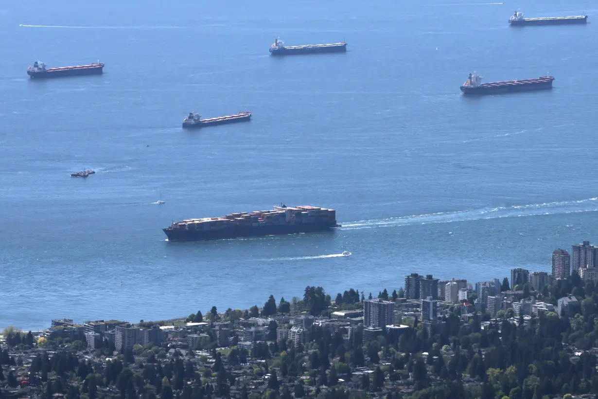 A container ship makes its way into the Port of Vancouver past vessels at anchor in English Bay