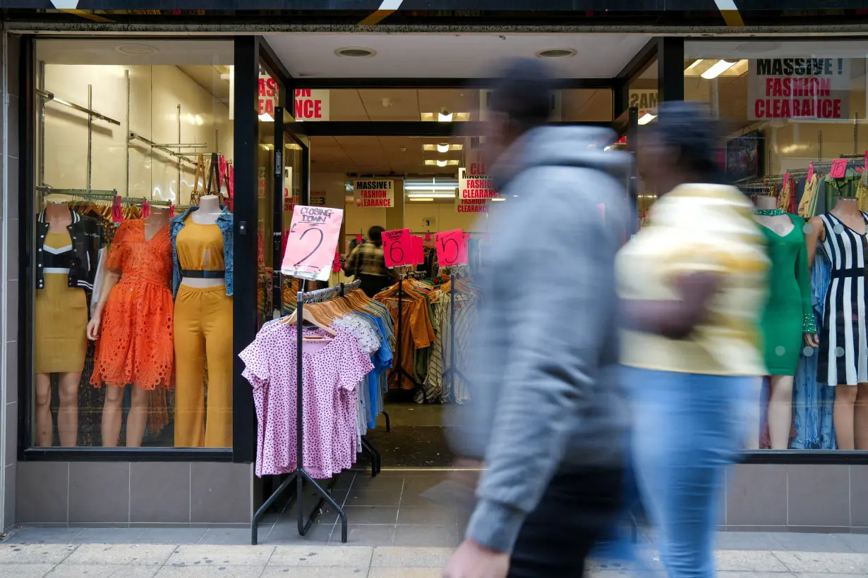 FILE PHOTO: People walk past a retail store with closing down sign in London