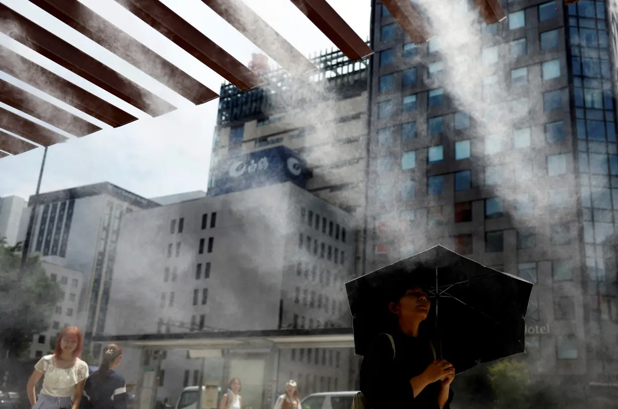 Passersby take a break under a cooling mist as the Japanese government issued a heatstroke alert in Tokyo