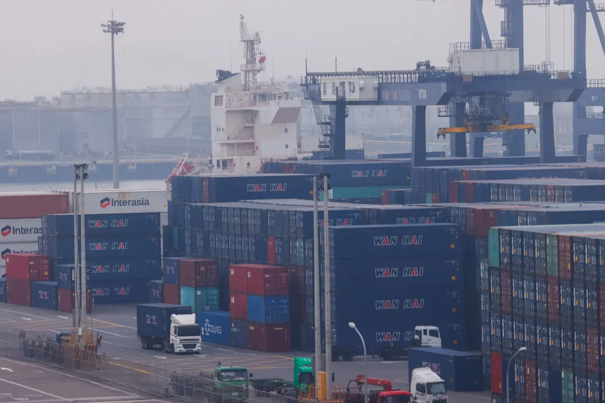 Trucks drive between cargo containers at Port of Taichung in Taichung