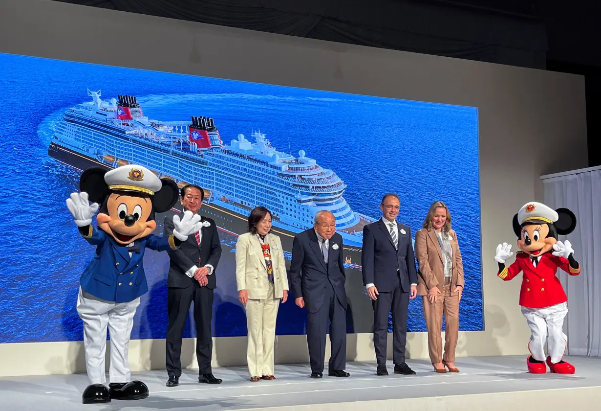 Disney and Oriental Land Co. executives pose with Disney characters at the unveiling of an expanded cruise line, in Urayasu