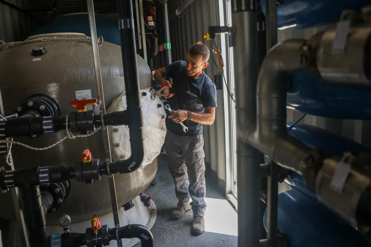 A worker inspects the hardware inside a desalination plant on the island of Naxos