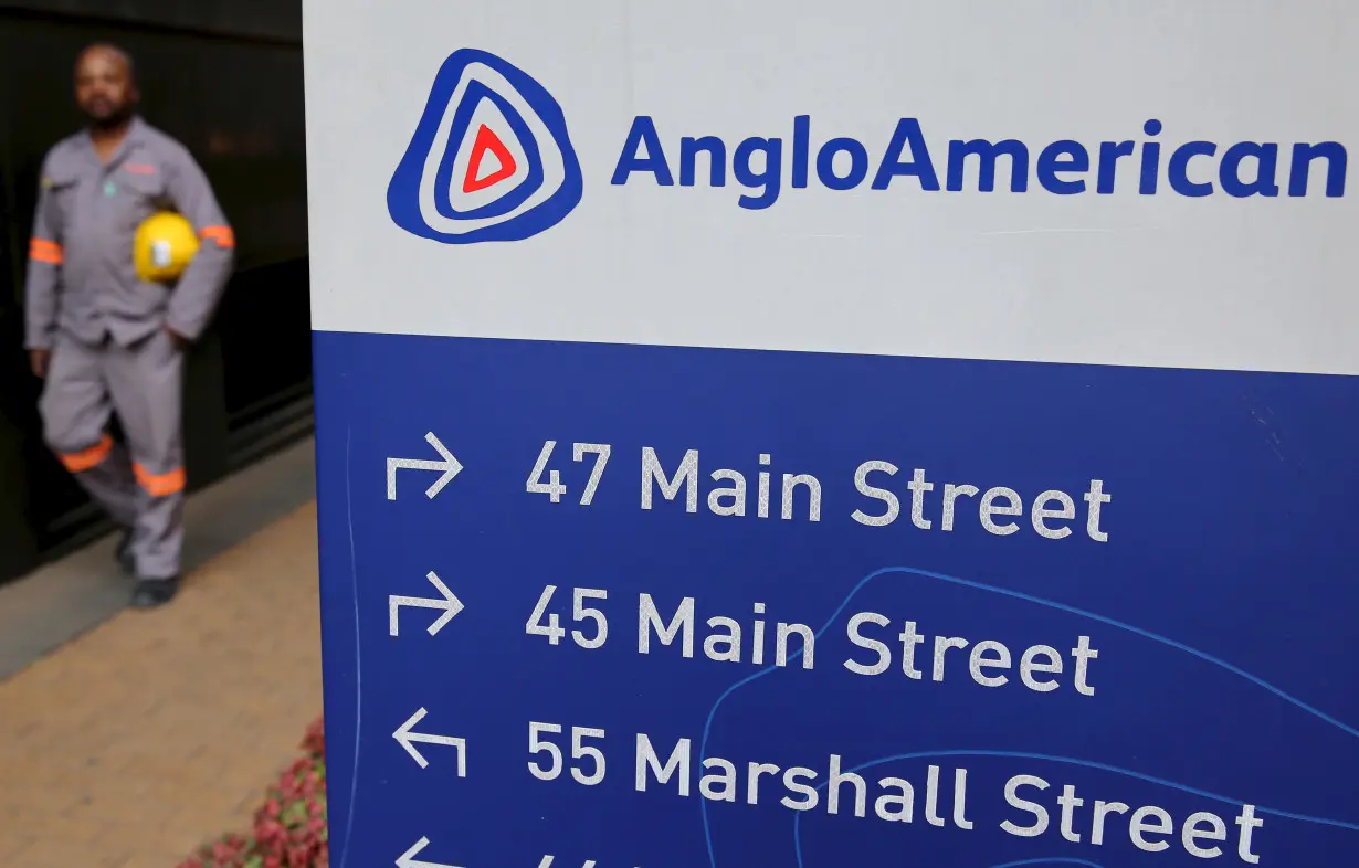 A worker walks past a board outside Anglo American offices in Johannesburg