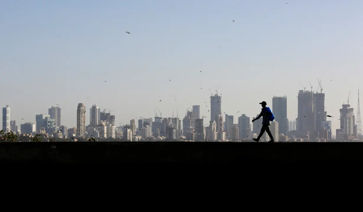 A man walks along a wall overlooking the central Mumbai's financial district skyline