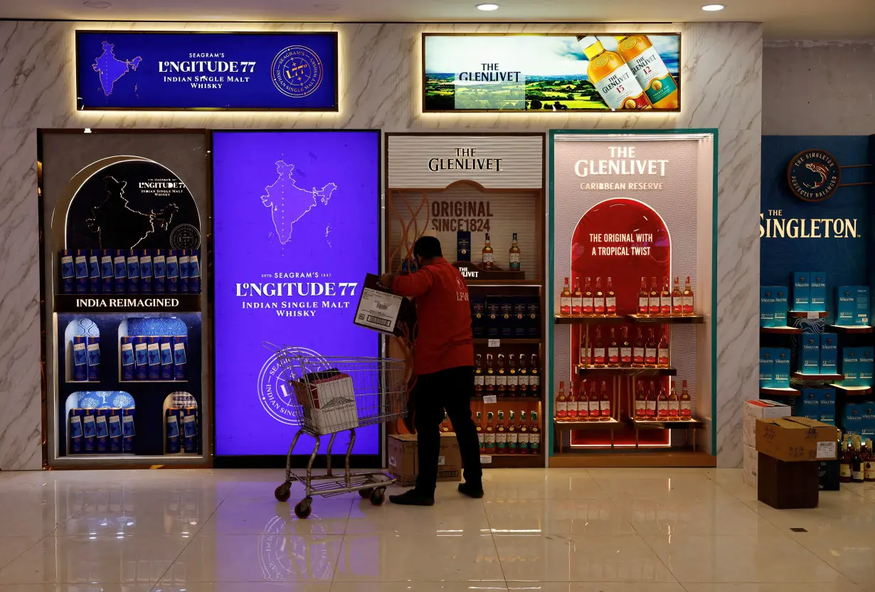 FILE PHOTO: A salesman stores whisky bottles for sale at a liquor store in Gurugram