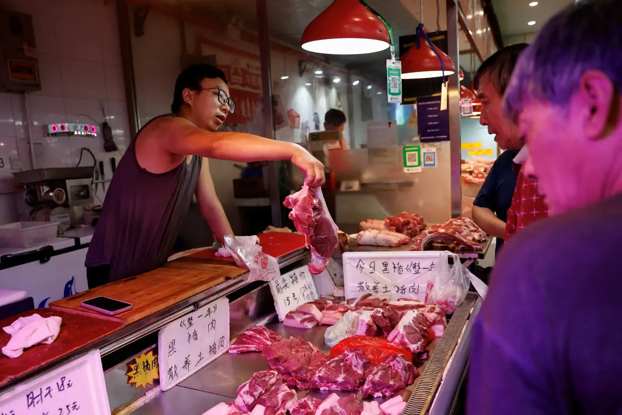 FILE PHOTO: Pork vendor attends to a customer at a morning market in Beijing