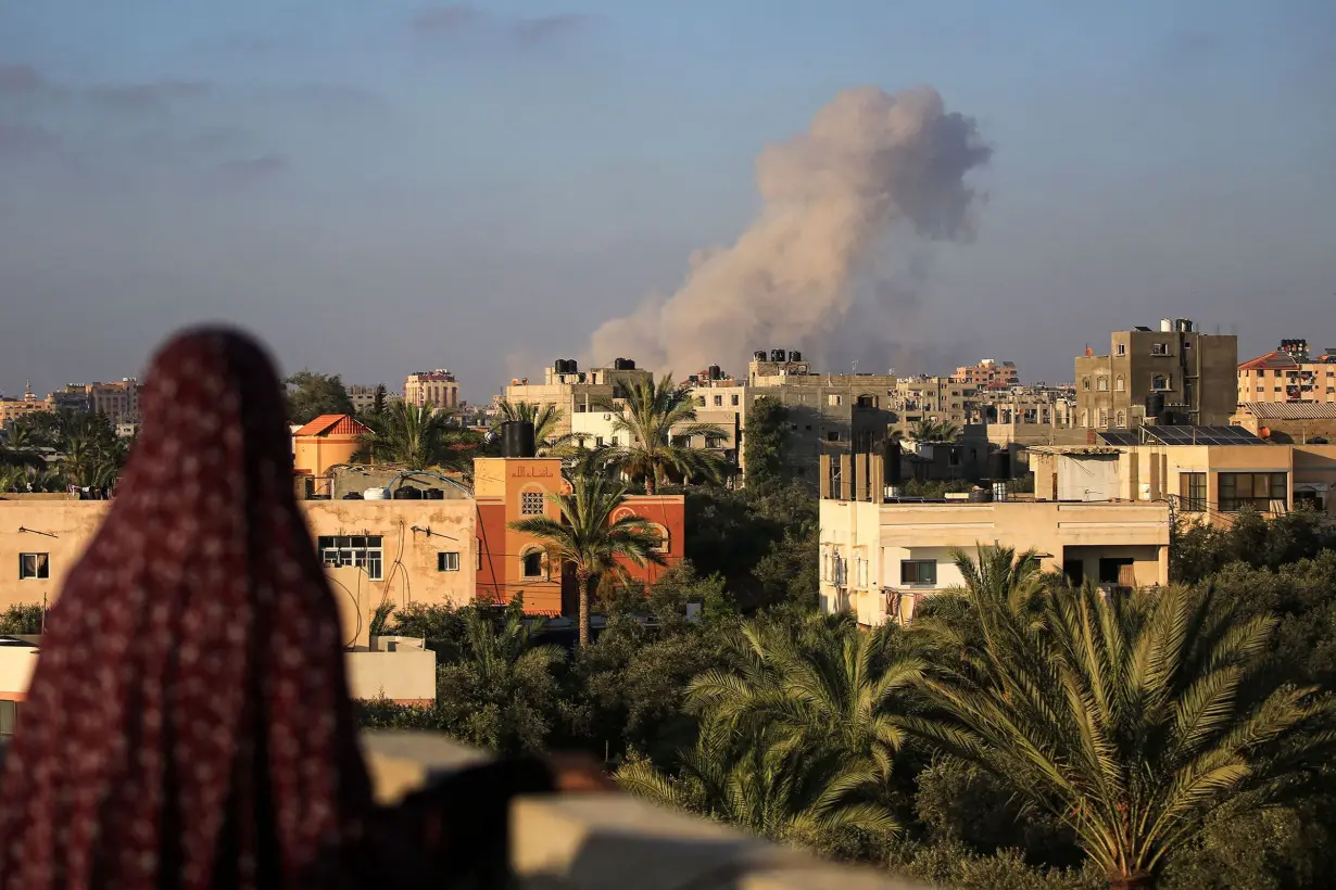 A Palestinian woman watches as smoke billows following an Israeli strike south of Gaza City.