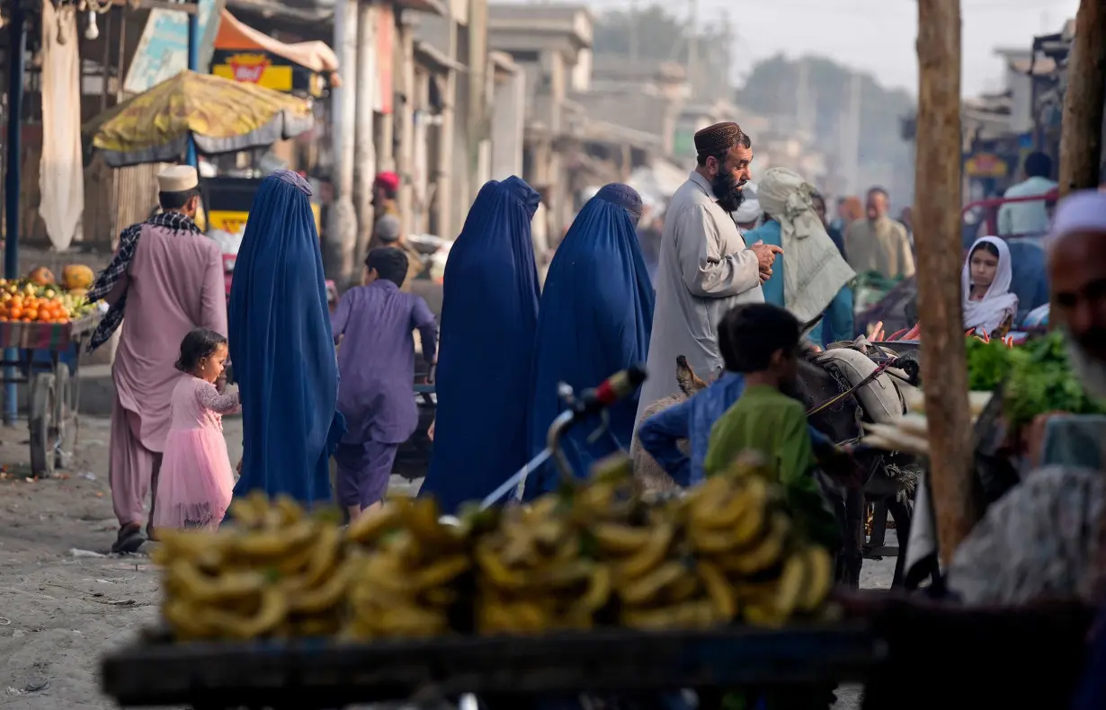 Burqa-clad Afghan women walk on a street with other in a a neighborhood, where mostly Afghan populations, in Karachi, Pakistan, Friday, Jan. 26.