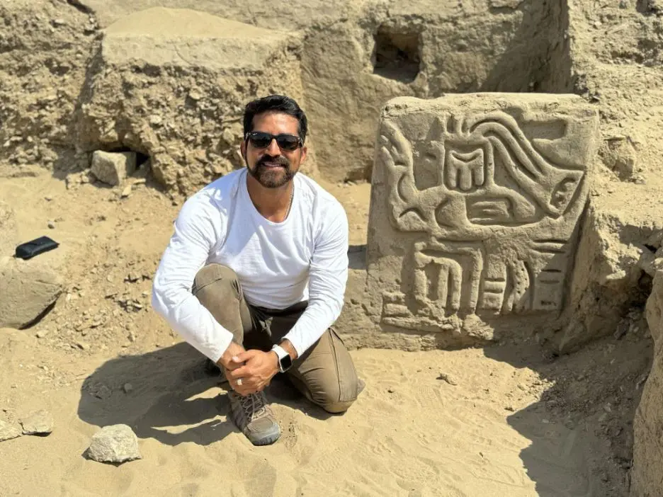 Field Museum scientist Luis Muro Ynoñán with the carving of a mythological bird creature in La Otra Banda, Cerro Las Animas.