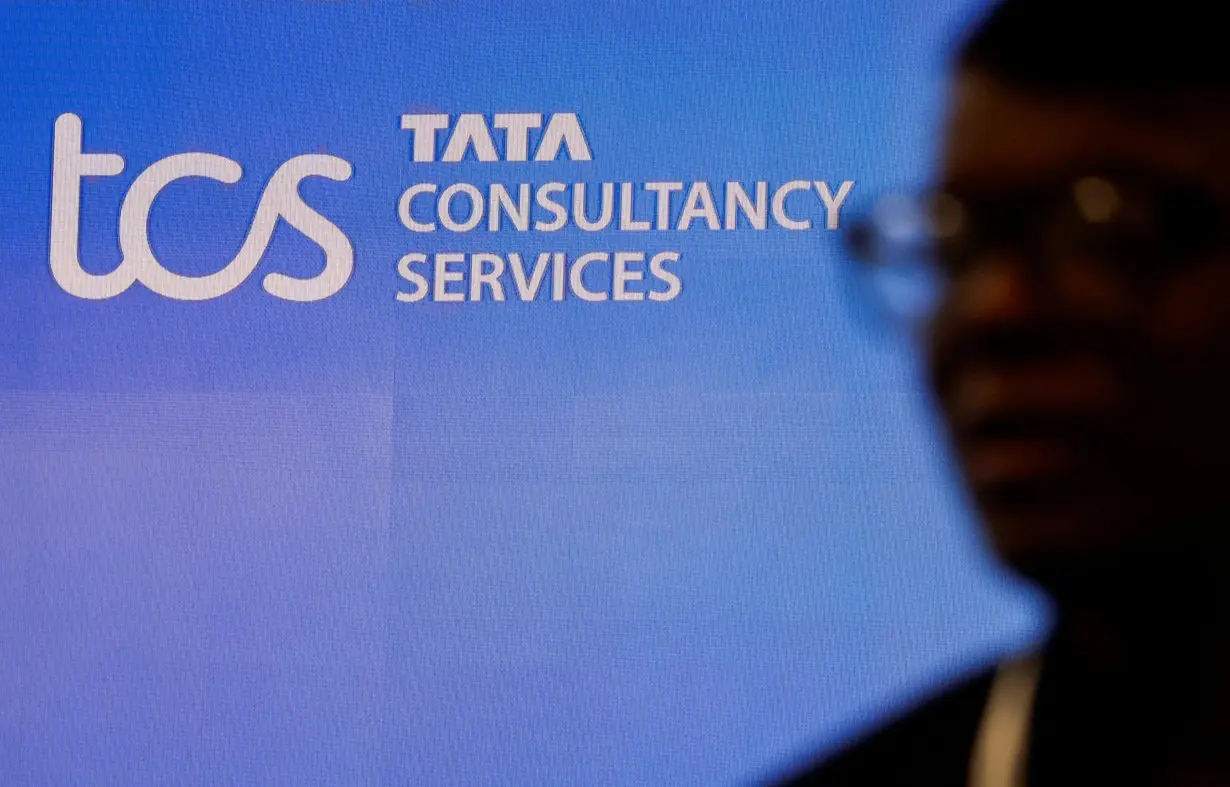 FILE PHOTO: A man walks past a logo of Tata Consultancy Services (TCS) before a press conference announcing the company's quarterly results in Mumbai