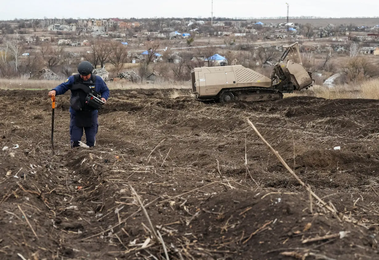State Emergency Service deminer uses a remote-controlled de-mining vehicle GCS 200 to work on a field near the village of Kamianka