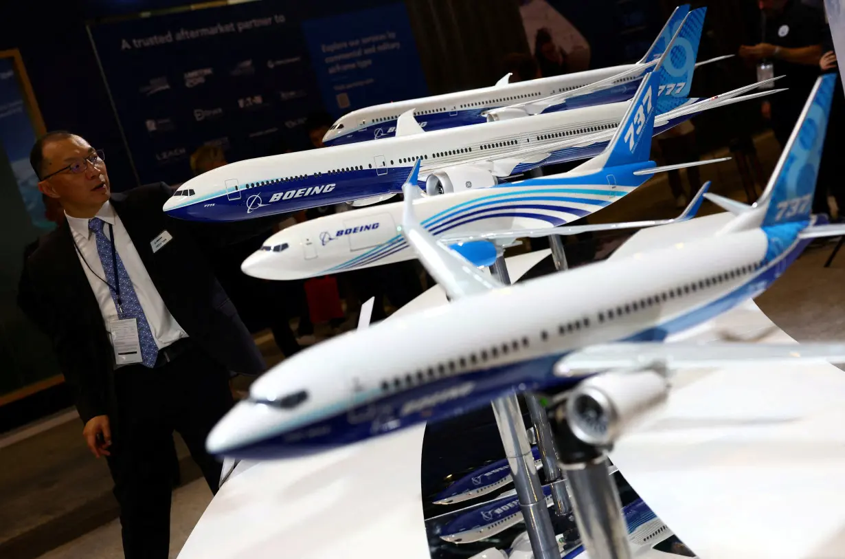 FILE PHOTO: A man passes Boeing model planes on display at the Singapore Airshow at Changi Exhibition Centre in Singapore